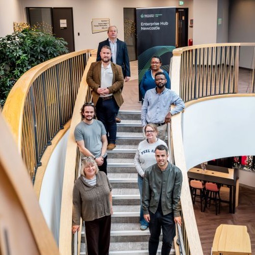 A group of people stood smiling on the stairs.